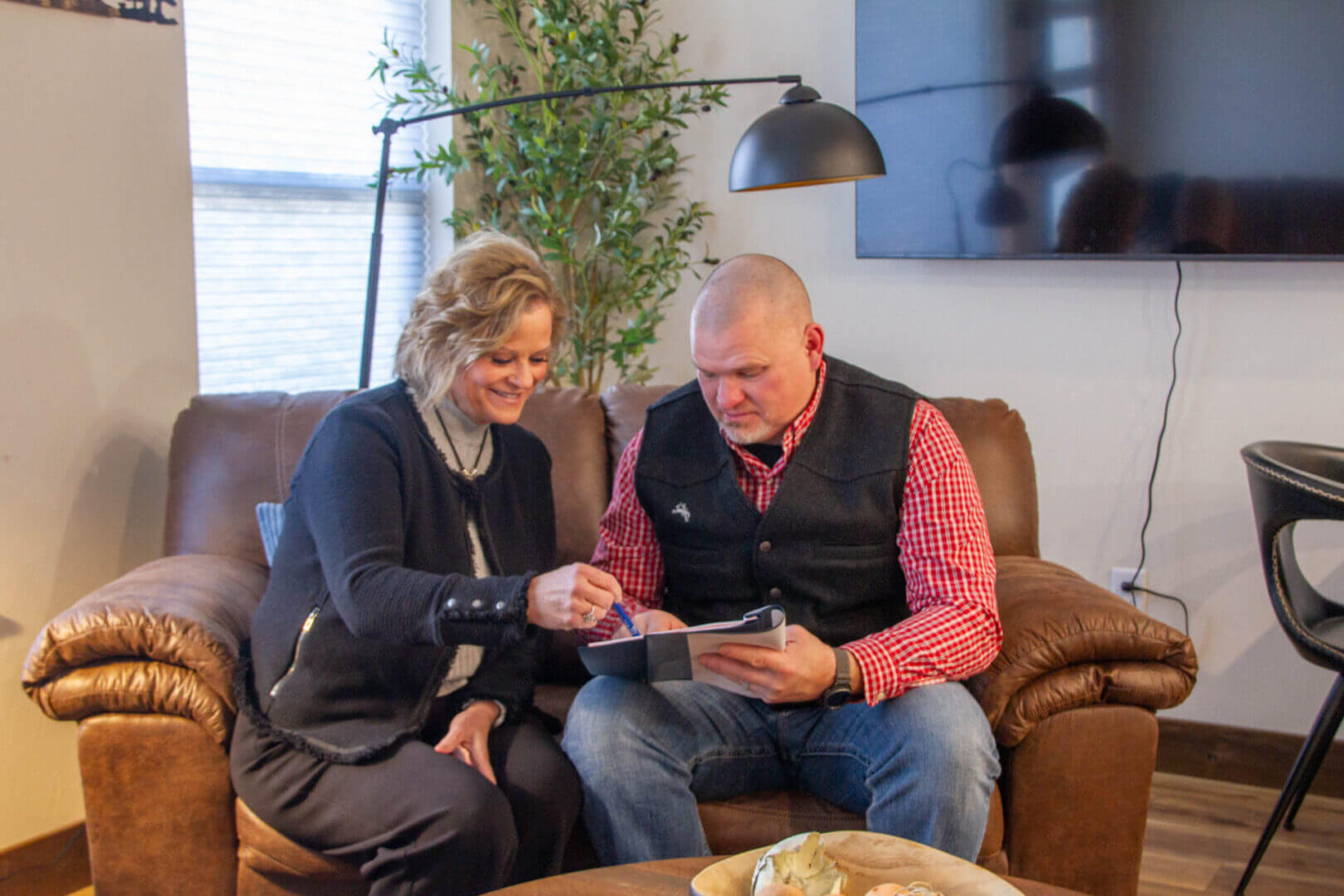 Two people reviewing documents on sofa.