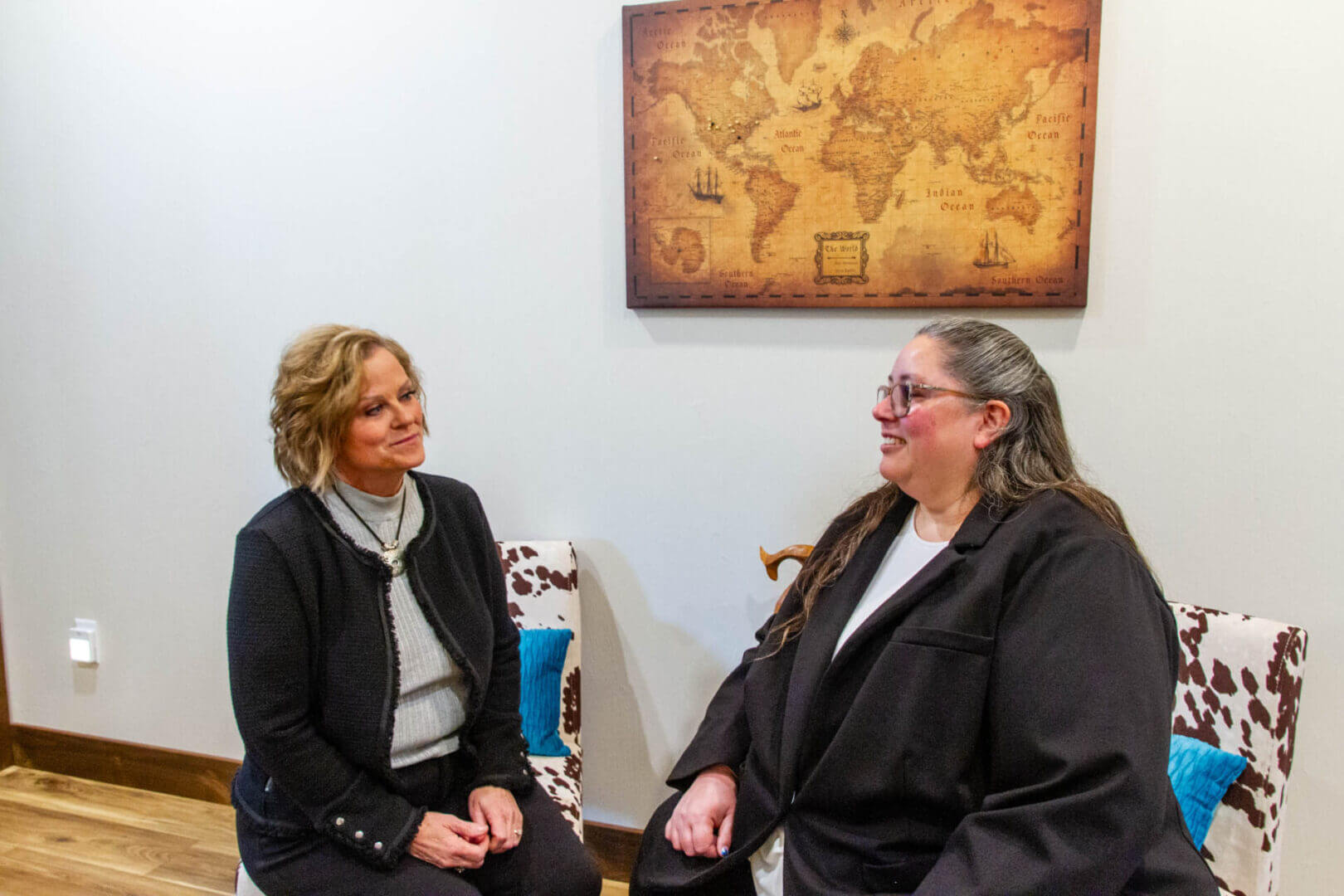 Two women sitting and talking indoors.